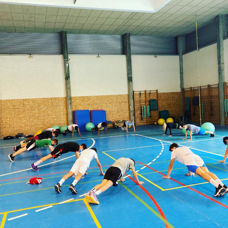 Niños haciendo flexiones durante un entrenamiento de un campamento baloncesto