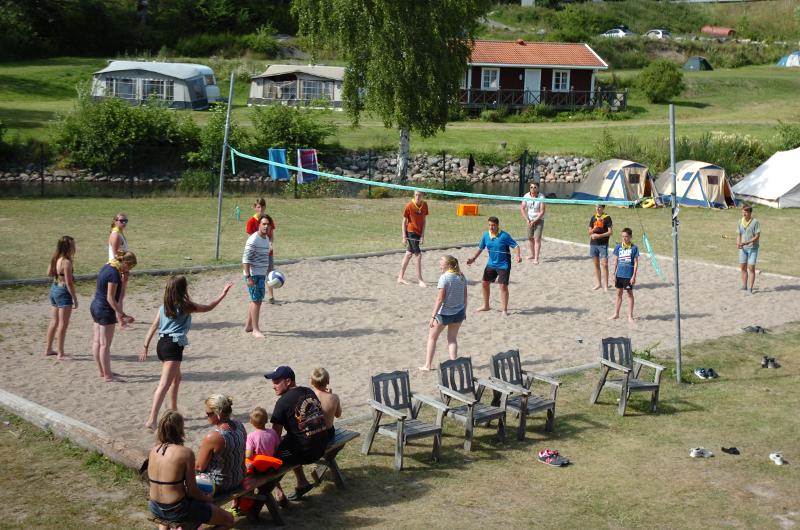 Grupo de jóvenes en una pista de voley playa jugando un partido en el campamento de atletismo