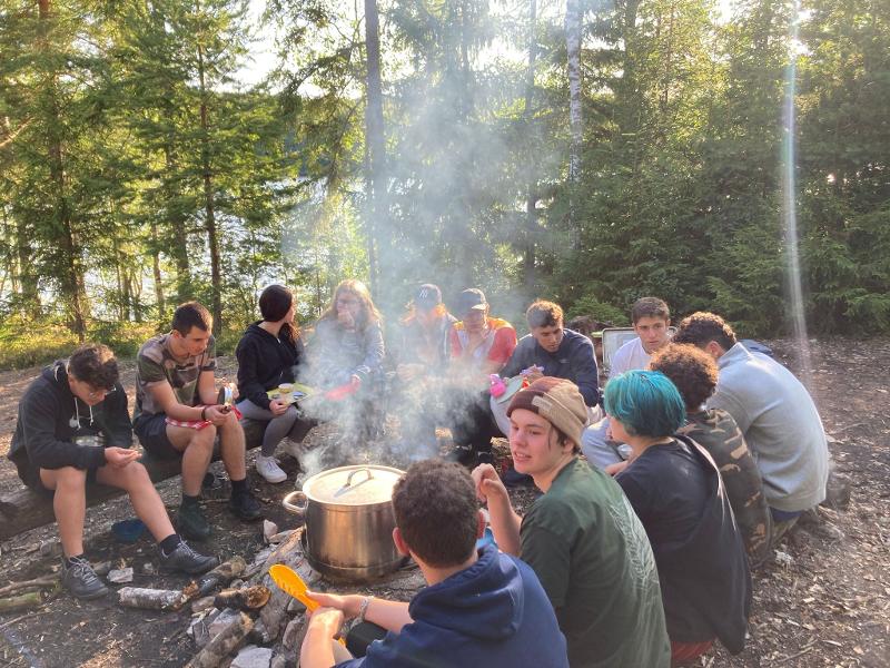 Jóvenes comiendo en el bosque en un campamento de verano en Suecia