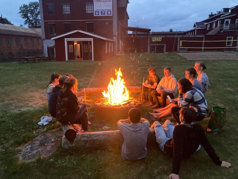 Jóvenes alrededor de una hoguera en un campamento de verano en Suecia