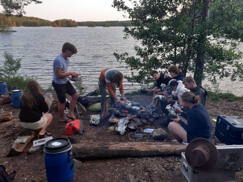 Jóvenes cocinando a orillas del lago en el campamento de verano en suecia