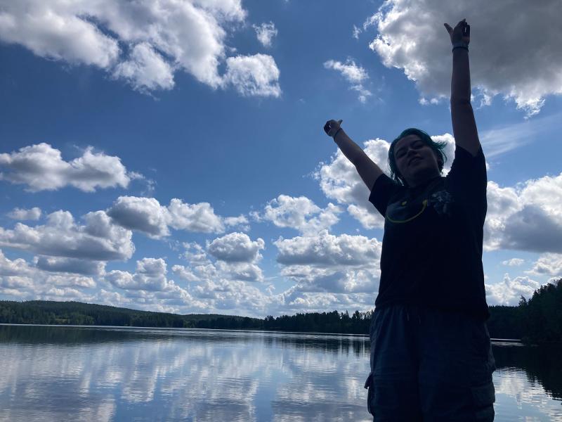 Joven posando delante del lago en el campamento de verano en Suecia