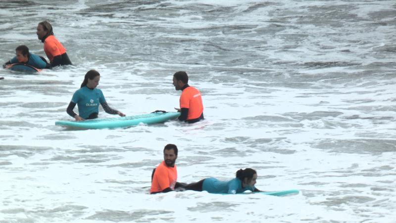 Participantes en medio del mar aprendiendo a saltar olas con los instructores en el asturias summer camp 
