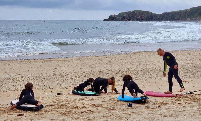 Participantes aprendiendo acsubirse a la tabla en una clase en la arena dada por la profesora en el summer camp asturias 
