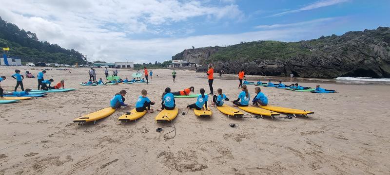 Niños en la arena preparándose para su siguiente clase de surf en el campamento de verano en asturias