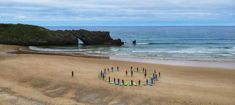 Niños en círculo aprendiendo surf durante un campamento de verano en asturias