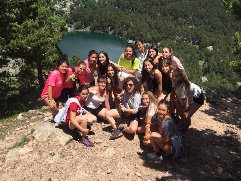Grupo de jóvenes posando en lo alto de una montaña con la laguna de fondo en el campamento de verano en Soria