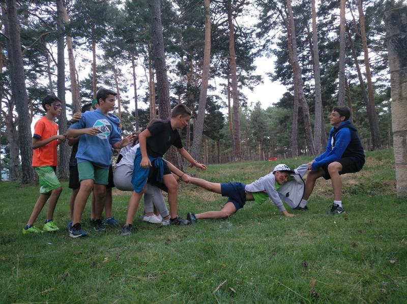 Jóvenes jugando en grupo mientras tiran de uno de ellos para elegir equipo en el campamento de verano en Soria