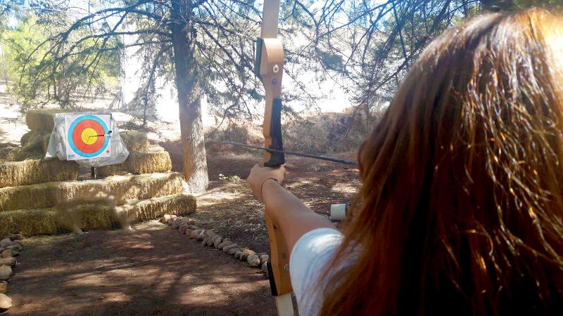 Niña practicando tiro con arco en las instalaciones del campamento en Albacete