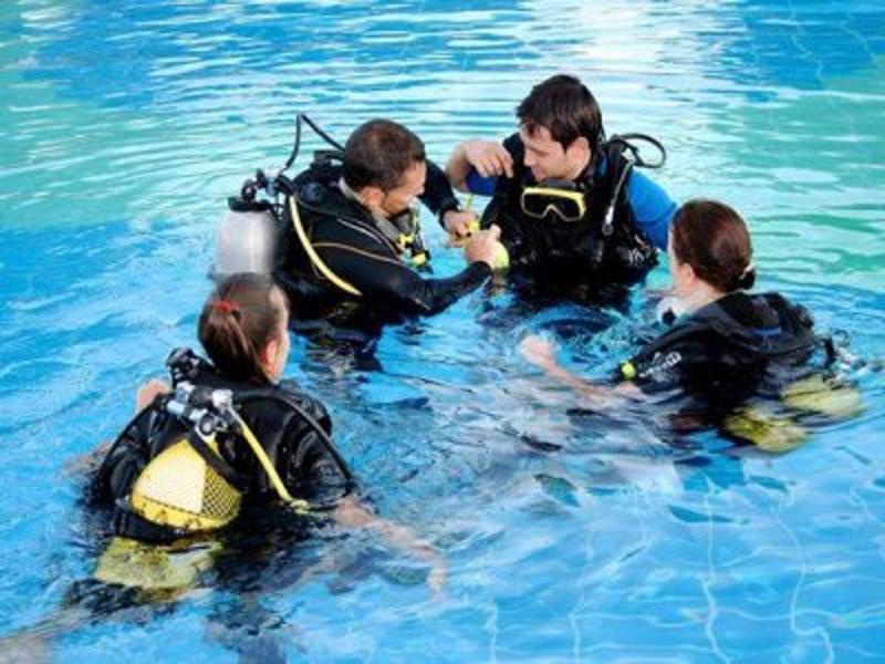 Jóvenes preparándose en la piscina para las clases de buceo con el instructor profesional del campamento en Albacete