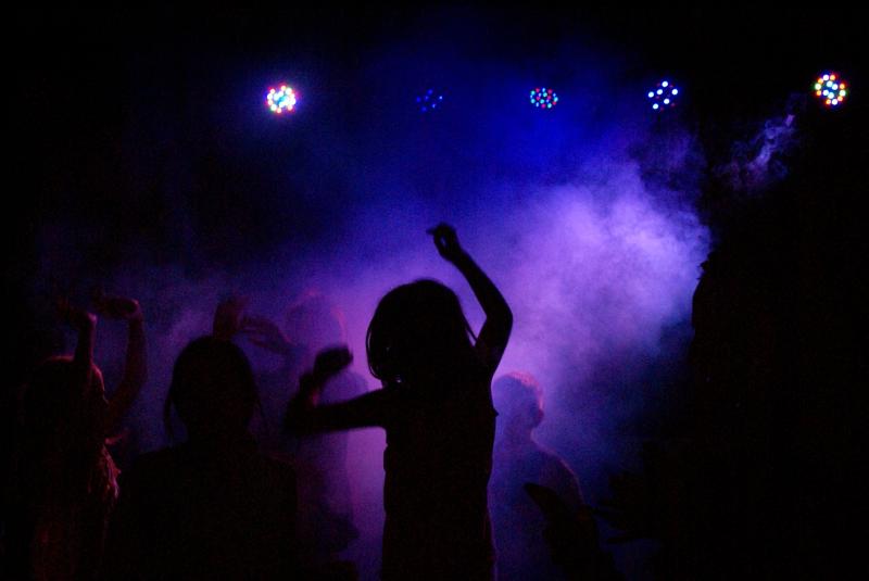 Grupo de jóvenes bailando en la oscuridad con las luces de la discoteca del campamento en Albacete