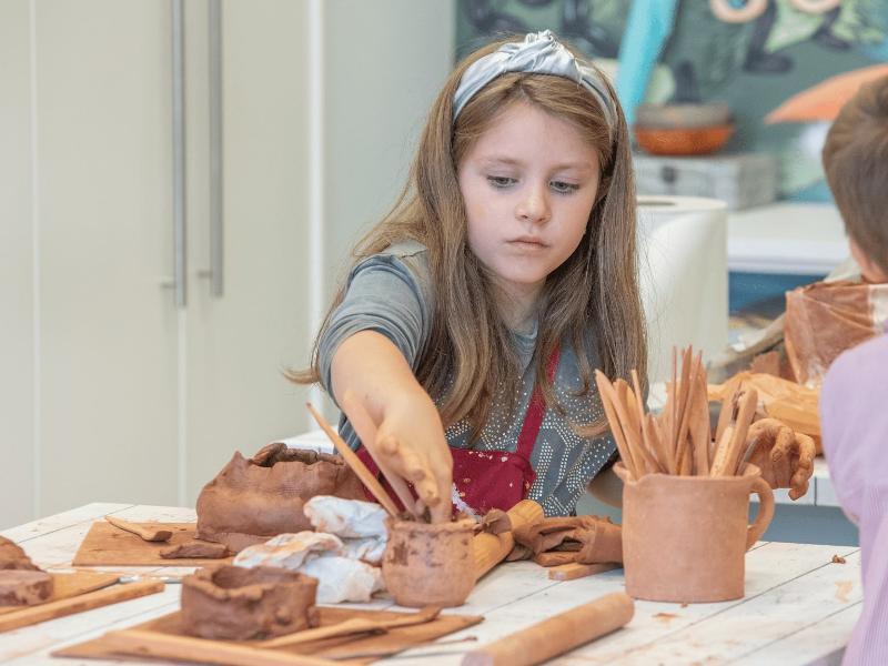 Niña realizando objetos de cerámica durante un campamento burgos