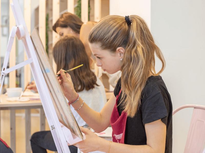 Niña pintando sobre un lienzo en un campamento en burgos