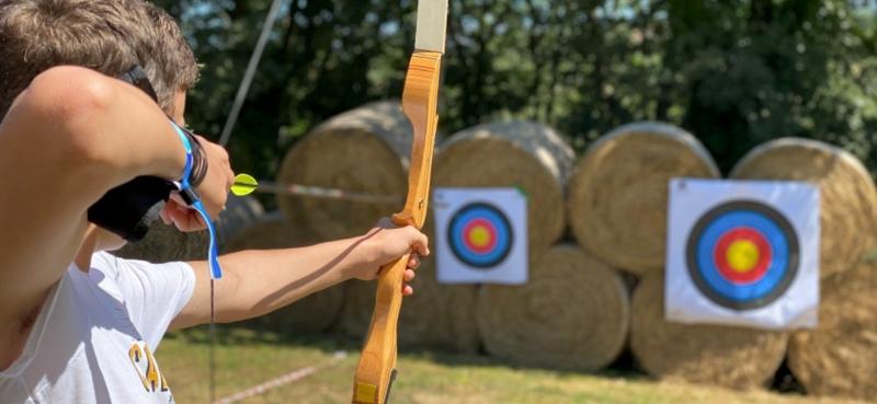 Niño practicando tiro con arco en un campamento multiaventura