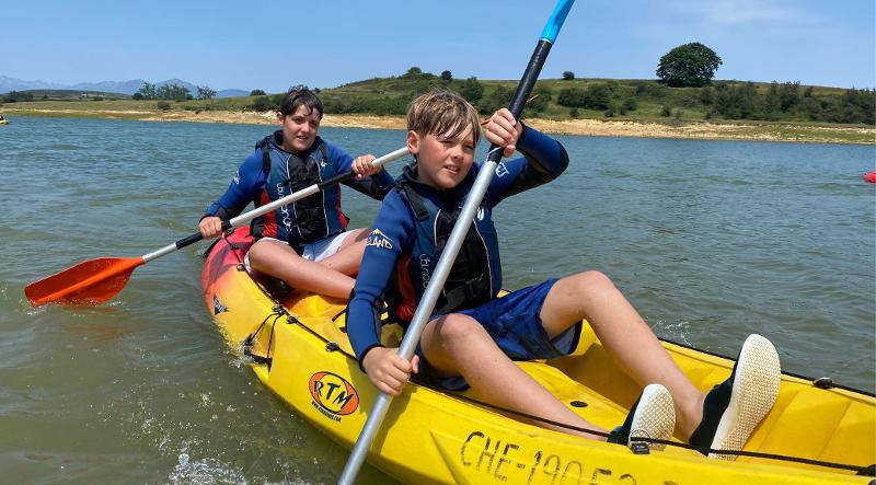 Dos niños remando en canoa durante un campamento verano multiaventura