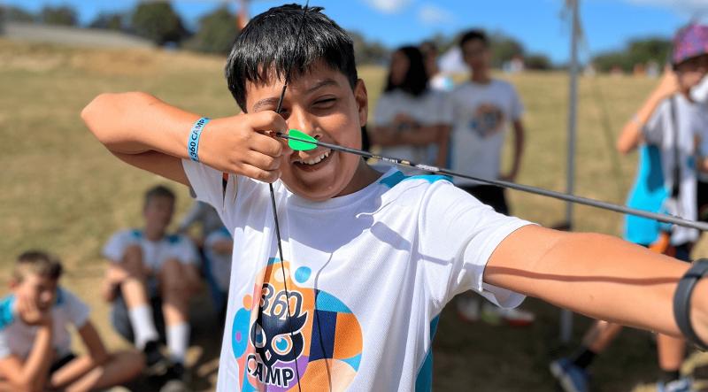 Niño apuntando con un arco durante un campamento multiaventura