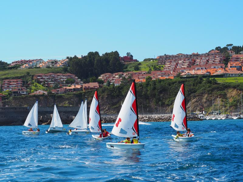 Jóvenes en navegando en pequeñas embarcaciones de vela en el campamento de verano en asturias 