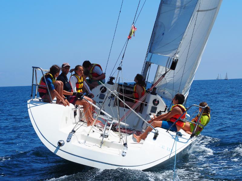 Jóvenes del campamento de verano en asturias navegando con sus monitores en un barco de vela