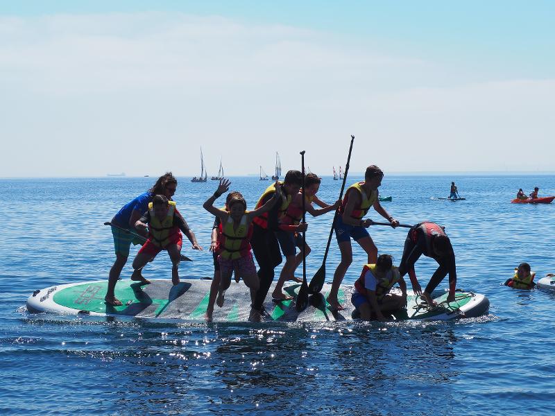 Jóvenes del campamento de verano en asturias tirándose al agua desde una tabla de BigSUP