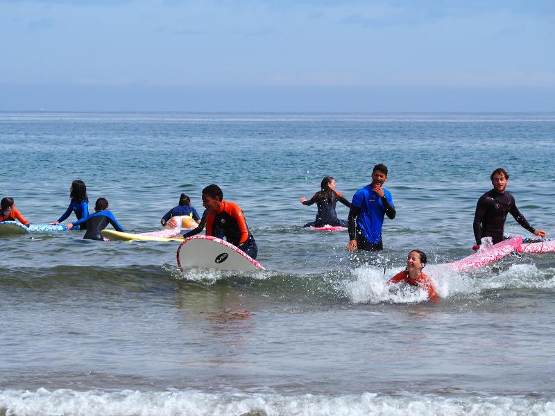 Participantes y monitores bañándose en la playa en el campamento asturias
