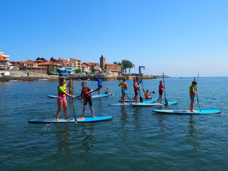 Jóvenes haciendo paddle surf en las actividades de día del campamento náutico en Asturias