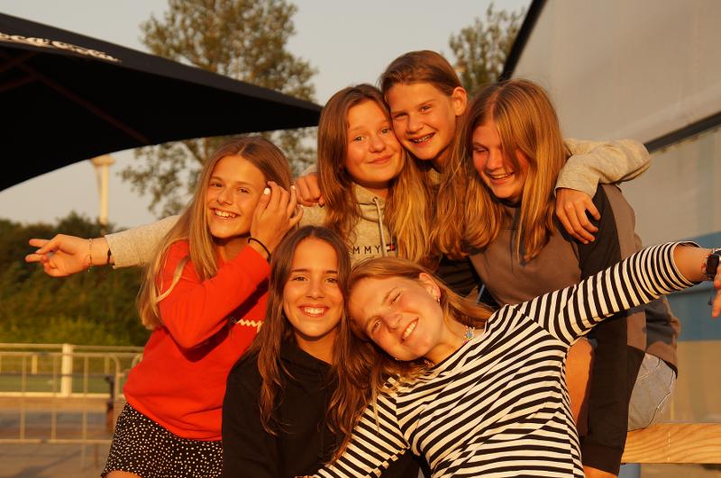 Grupo de seis niños abrazándose sonrientes en el exterior del campamento de verano en Países Bajos