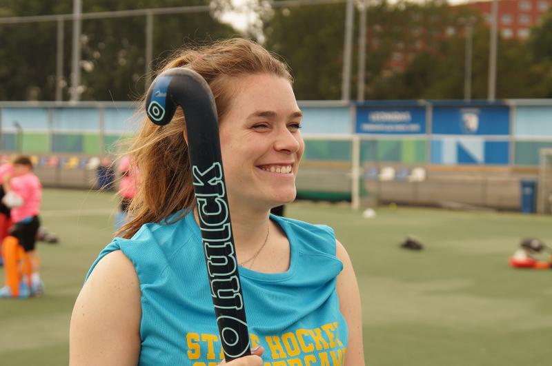 Joven adolescente sonriendo con un stick de hockey en el campamento de verano en Holanda