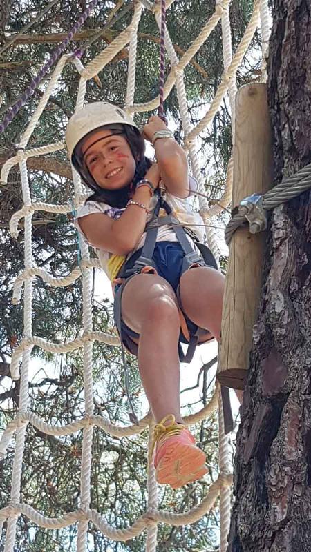 Niña posando divertida colgada desde el parque de cuerdas en Madrid