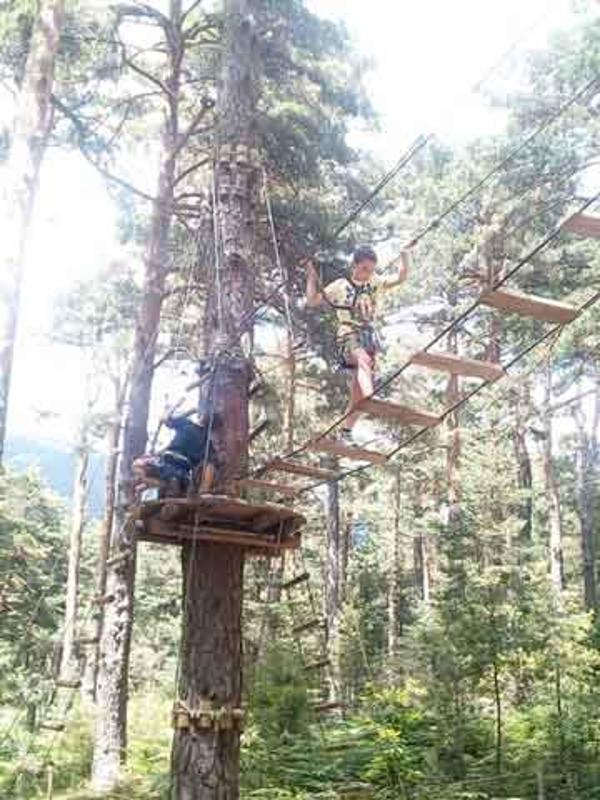 Jóvenes caminando por el parque multiaventura en medio de la naturaleza del campamento de verano en Madrid