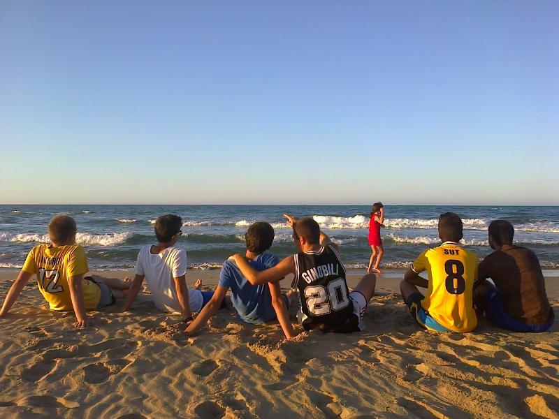 Un grupo de jovenes mirando el atardecer en una playa en un campamento de verano en valencia barato