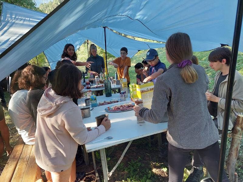 Un grupo de niños en una mesa en una tienda de campaña en un campamento naturaleza para niños