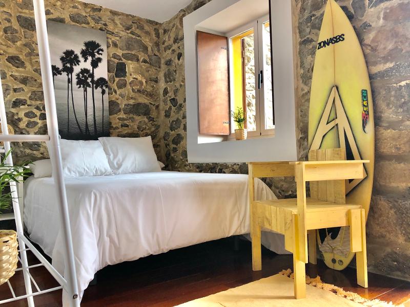 Habitación con cama doble y tabla de surf para los alumnos del campamento acuático