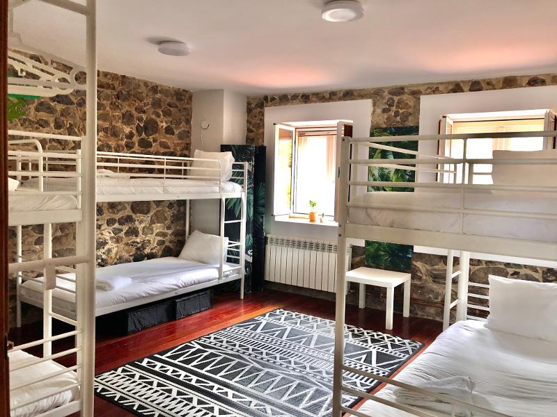 Habitación séxtuple con literas individuales individuales para los jóvenes que viven el campamento de surf en Cantabria