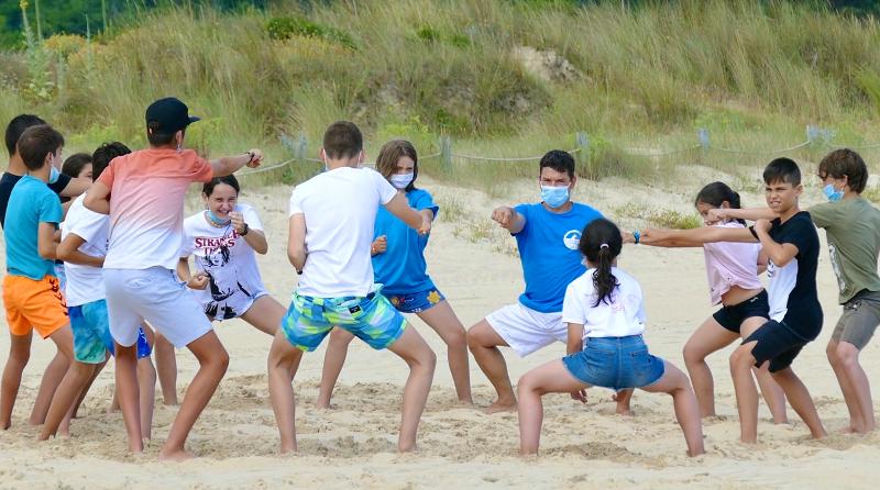 Grupo de jóvenes calentando en circulo con el monitor del campamento de verano en Cantabria
