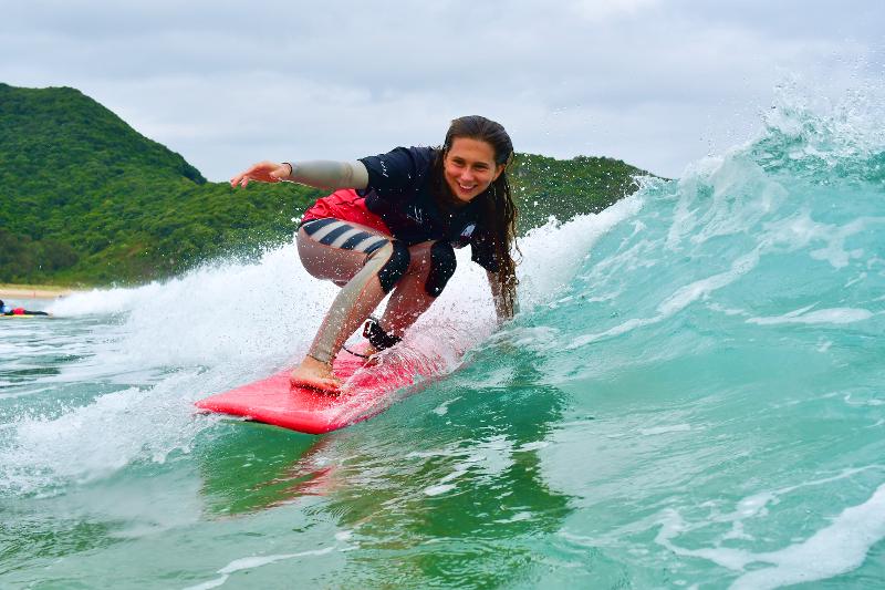 Joven surfeando feliz con la supervisión del instructor del campamento de verano en Cantabria