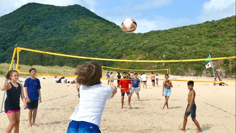 Grupo de jóvenes disfrutando de un partido de voley playa durante el campamento deportivo en Cantabria