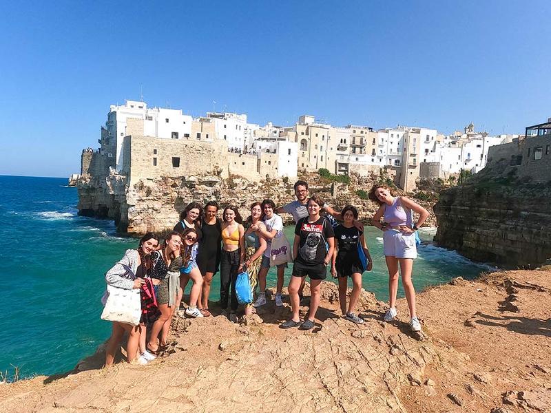 Grupo de jóvenes posando ante la cámara durante una excursión a un pueblo de la costa en el campamento en Italia