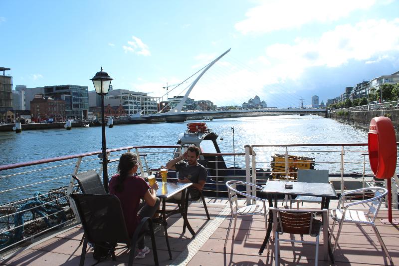 Dos personas manteniendo una conversación al lado del río con dos cervezas en el curso de ingles en dublin 