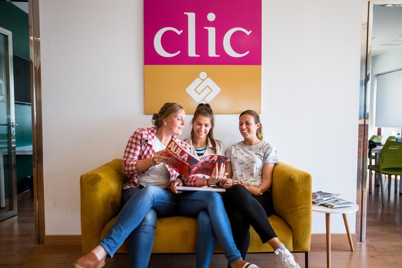 Chicas en el sofá leyendo una revista juntas en el curso de español en españa