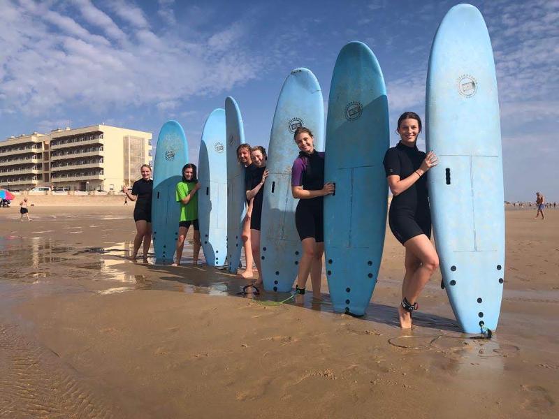 Seis chicas con tablas de surf en la playa en el curso de español en españa