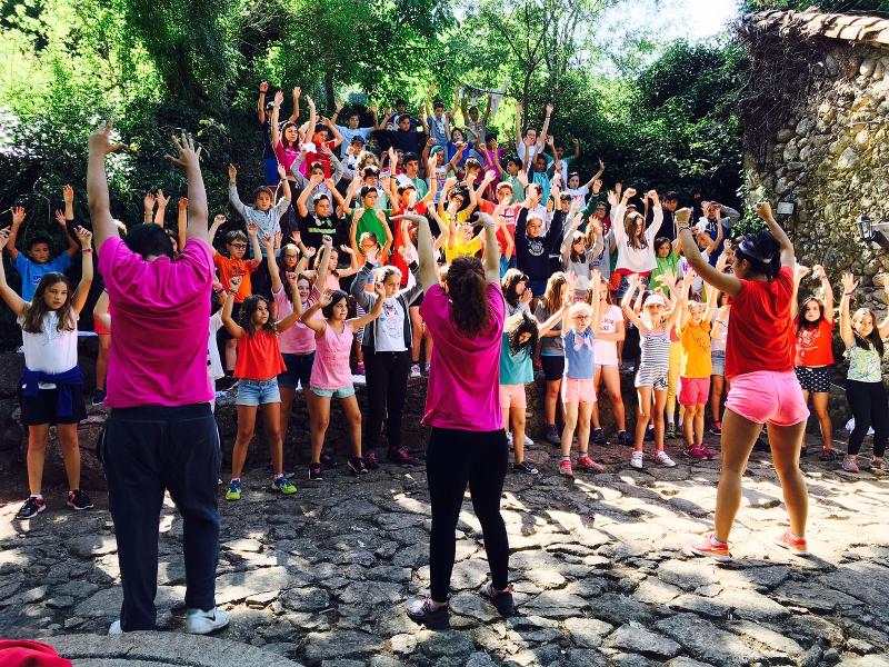 Niños y niñas divirtiéndose en grupo con sus monitores en el campamento comunidad madrid