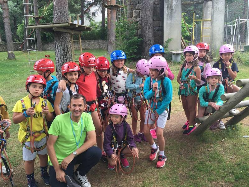 Grupo de participantes de primaria junto con el monitor del campamento en Cazorla preparándose para divertirse en el circuito de tirolinas y escalada