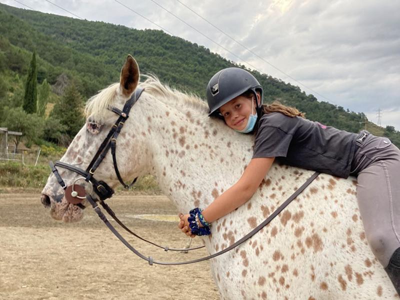 una niña abrazando a un caballo en un campamento de verano aragon