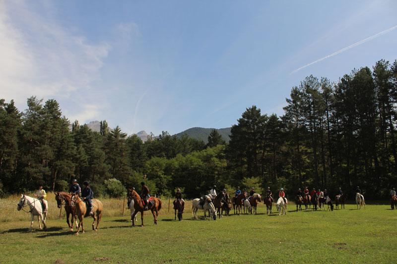 una foto de un grupo de jovenes montando a caballo en un campamento hipico