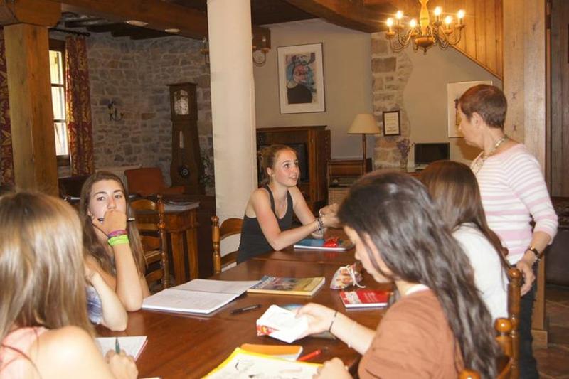 Jóvenes reunidas en una mesa estudiando nuevos conjuros en el campamento de magia