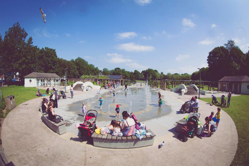 Gente en una plaza con una fuente bañándose en ella en el curso de ingles inglaterra