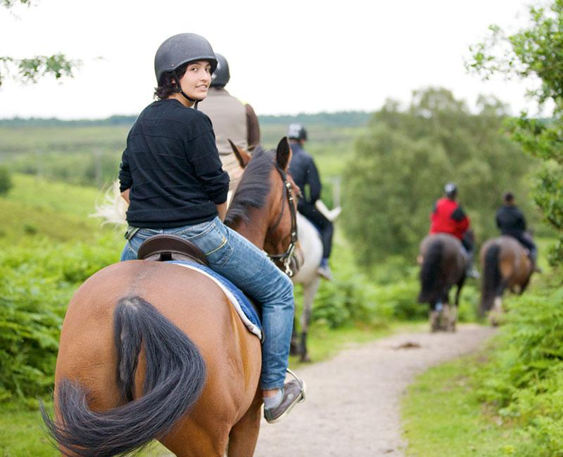 Grupo de jóvenes montando a caballo por el campo en el curso verano inglaterra 
