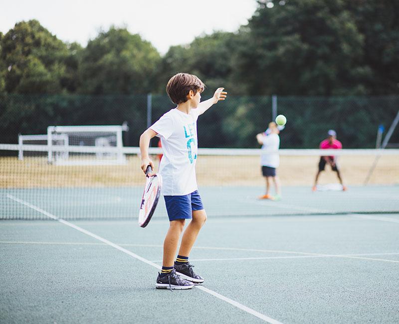 Niño jugando al tenis en el curso ingles en extranjero