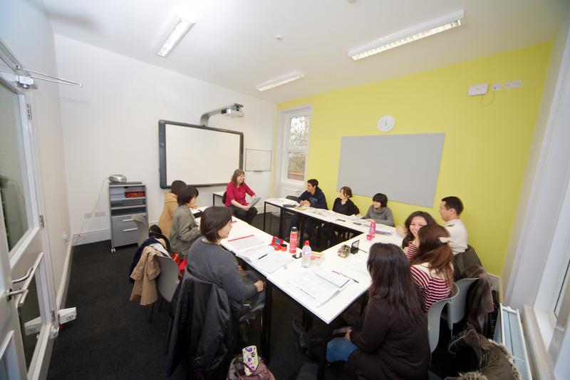 Jóvenes con su profesora dando clase en el curso de ingles extranjero