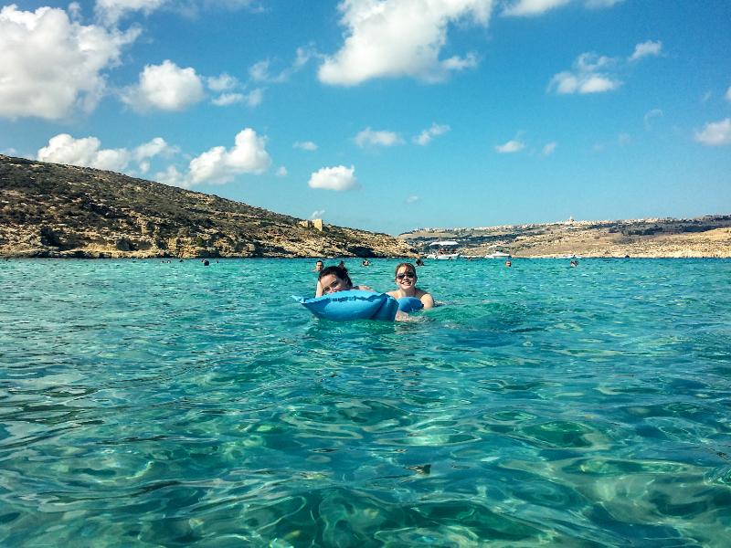 Jóvenes bañándose en la playa con una colchoneta en el curso de idiomas en malta